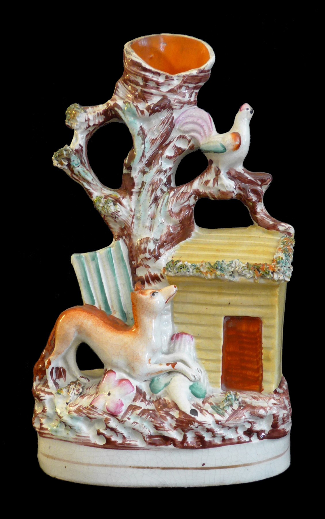 multicolored ceramic figure with fox looking up at rooster in tree; body of tree is a vase