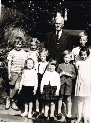 JRG and English Children standing for a photo is a man with white hair and seven children