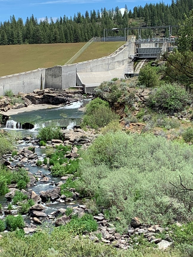 a concrete dam with a flowing river below