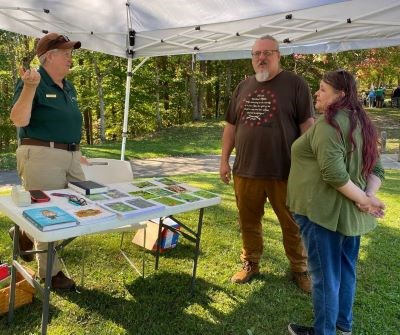Jacki Wright A woman in a Volunteer-in-Parks uniform speaks with two park visitors.