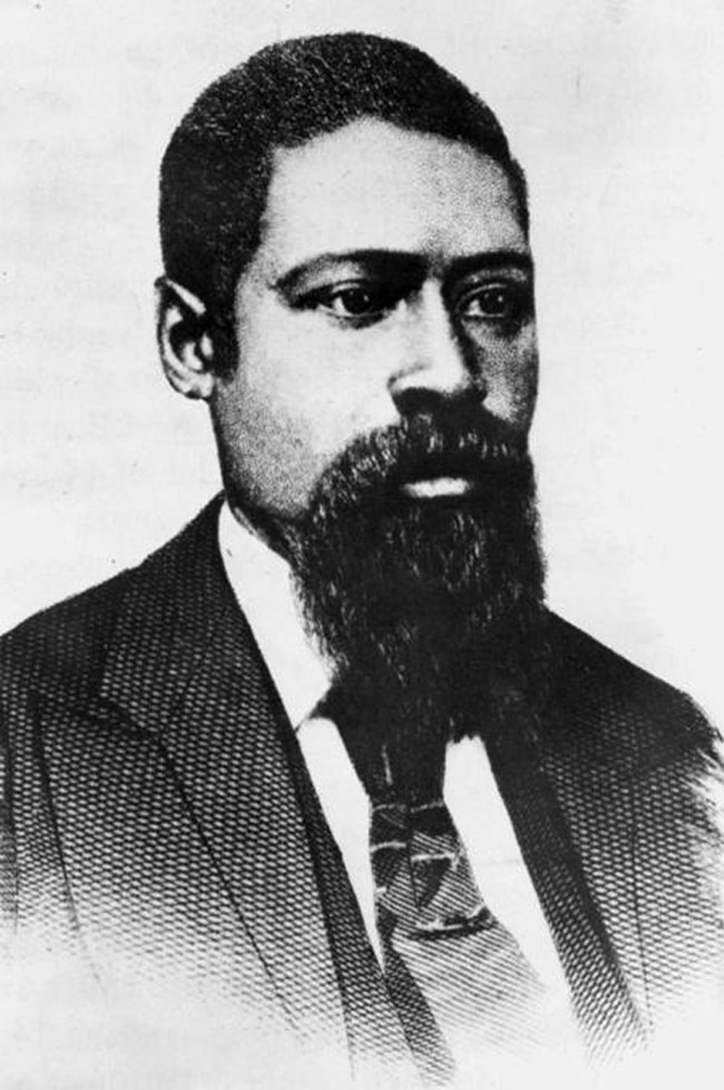 Bearded African American man wearing suit and tie.