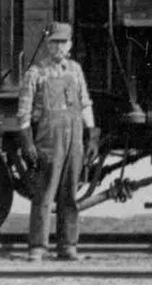 a man in overalls atands in front of a train engine