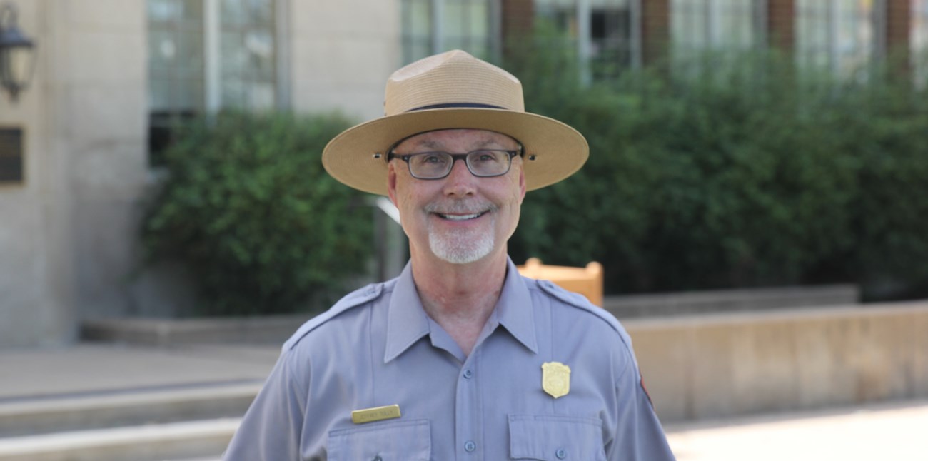Photo of a smiling park ranger in front of a building
