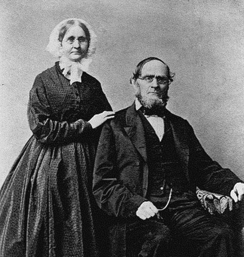 Black and white portrait of a man and woman both in glasses and 19th century clothes
