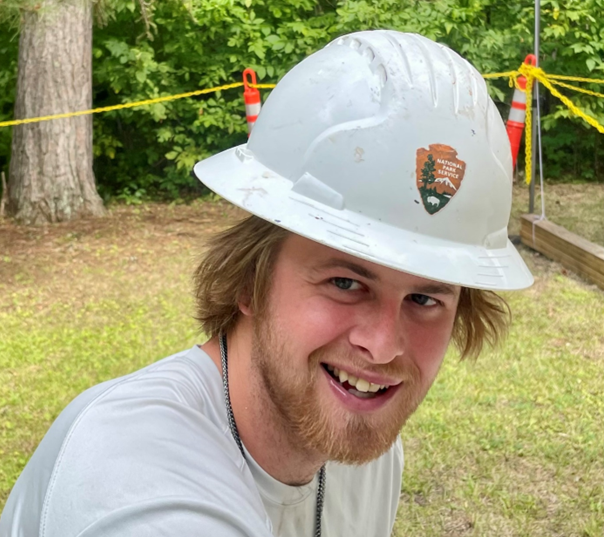 Joe Glowack Worker smiles into the camera while wearing a white hardhat with national park service Arrowhead emblem on the front.