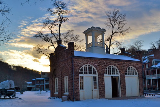 Rectangular brick building topped by cupola in the snow.