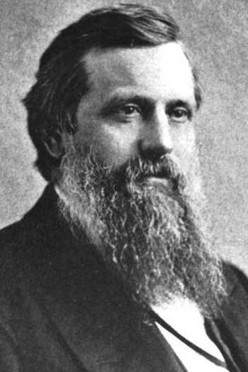 Bearded man wearing black suit.