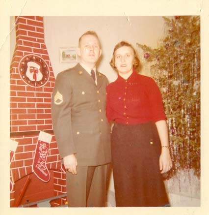 a young couple stand together in front of a Christmas tree