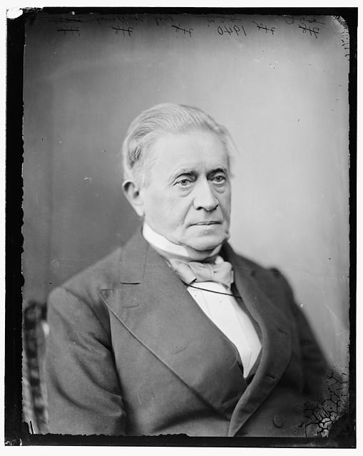 A black and white photograph of a man wearing a suit and bowtie.