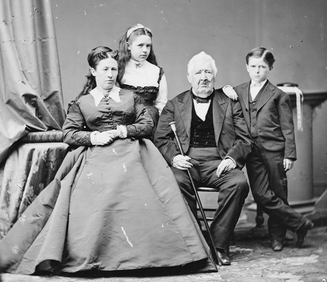 Black and white photo of a woman and older man in chairs with two children standing between them
