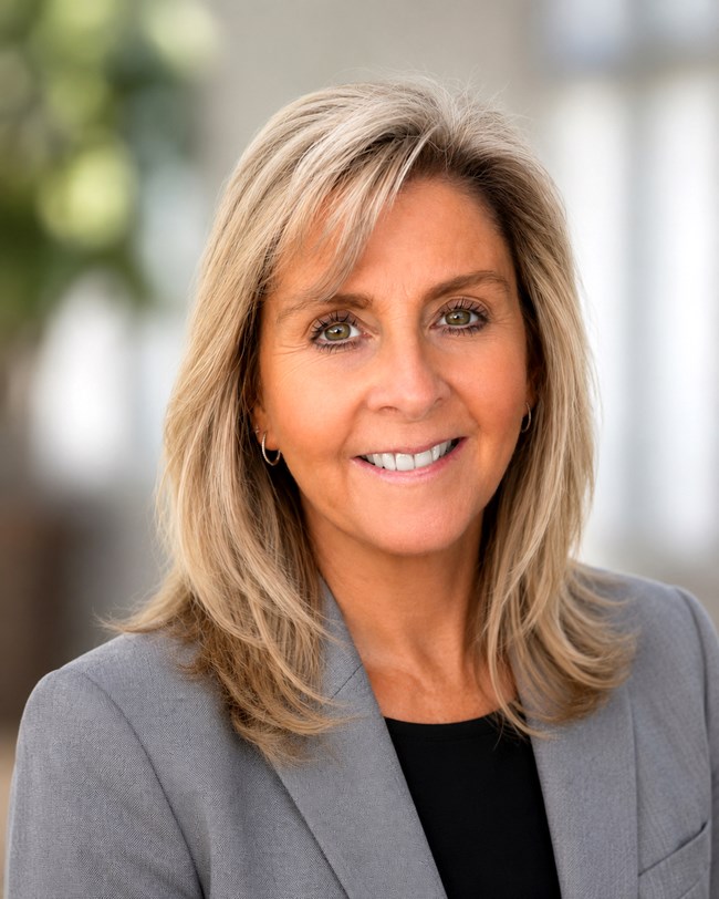 Headshot of smiling woman with long blond hair in gray suit jacket
