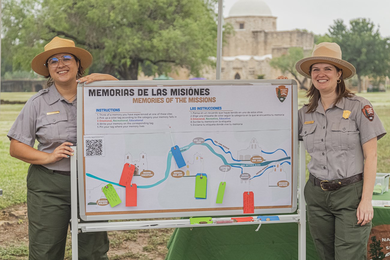 Two rangers stand next to map exhibit Two rangers in between a map exhibit