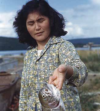 Vera Angasan with fish, 1950 A woman with eyes closed extends her arm, holding a silver fish under the gills
