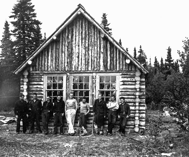 FWS crew at field laboratory, c. 1943 A row of nine men leaning against the front of a log structure