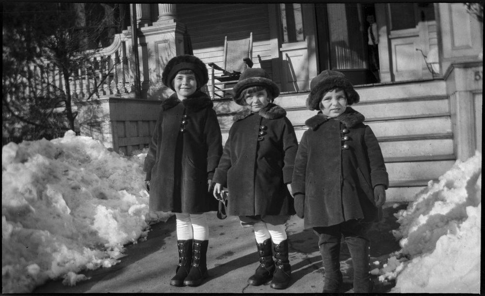 Rosemary, Kathleen, and Eunice Kennedy stand in matching winter coats beside snow banks.