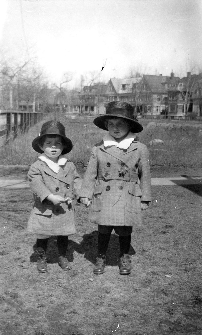 Joe Jr. and John Kennedy stand in a field wearing formal Easter clothes.