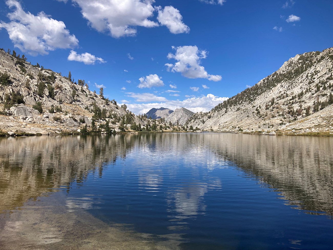 Kid Lakes Basin, Kings Canyon National Park View of a large lake with clear water reflecting sky, clouds, and mountains.