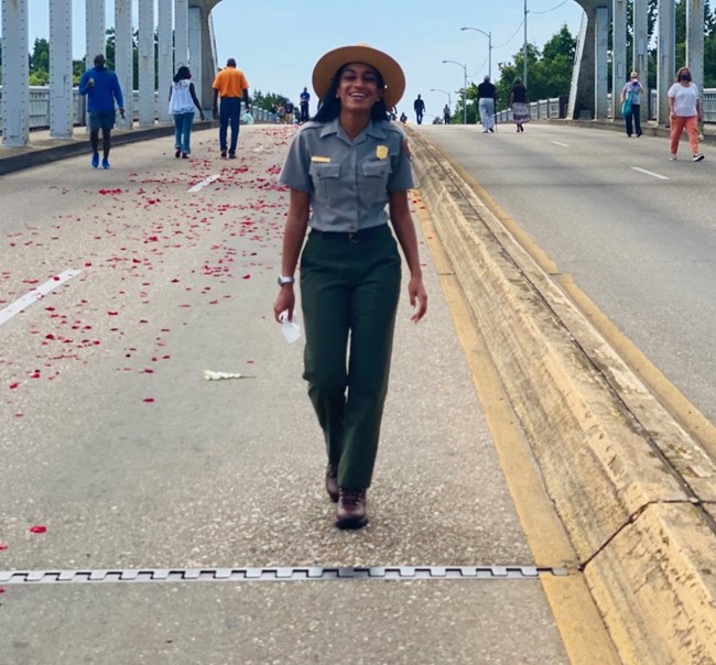 woman with park ranger outfit walking by the Edmund Pettus Bridge