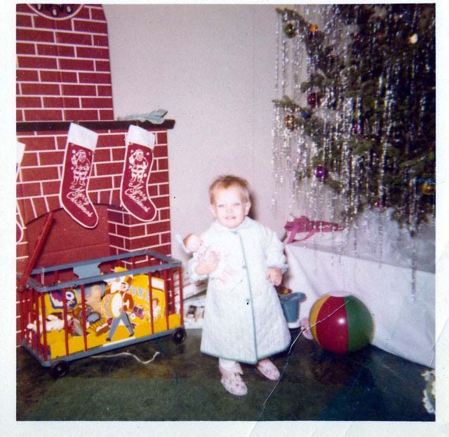 a young child stands in front of a fireplace with stockings