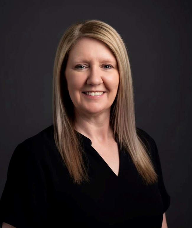Headshot of woman with long blond hair in black garment