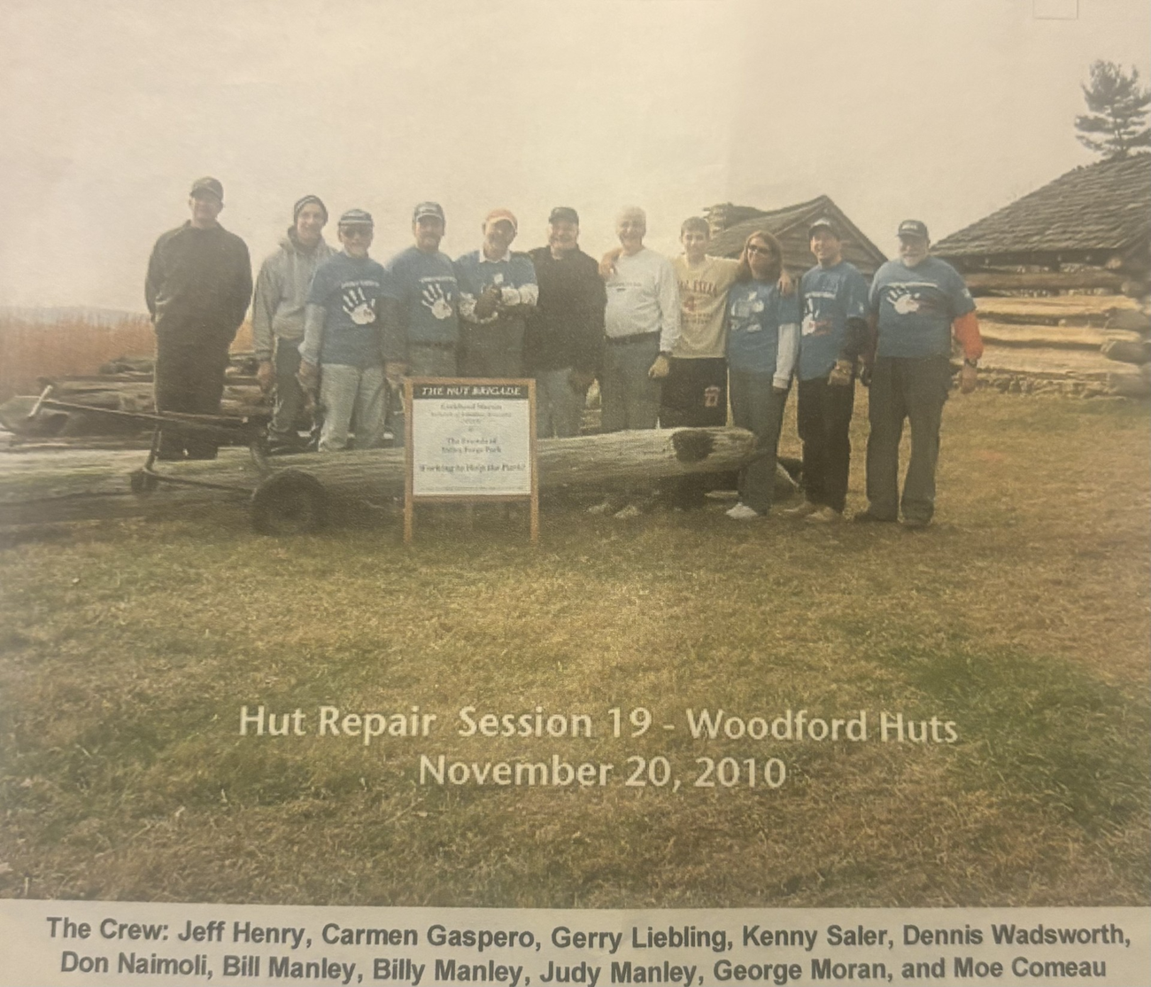 a group of people stand in front of wooding huts.
