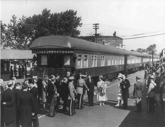 King George and Queen Elizabeth stand in front of a train car