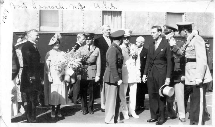 King George and Queen Elizabeth stand with men in uniforms