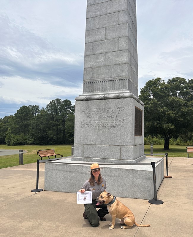 Park ranger and dog taking photo in front of monument