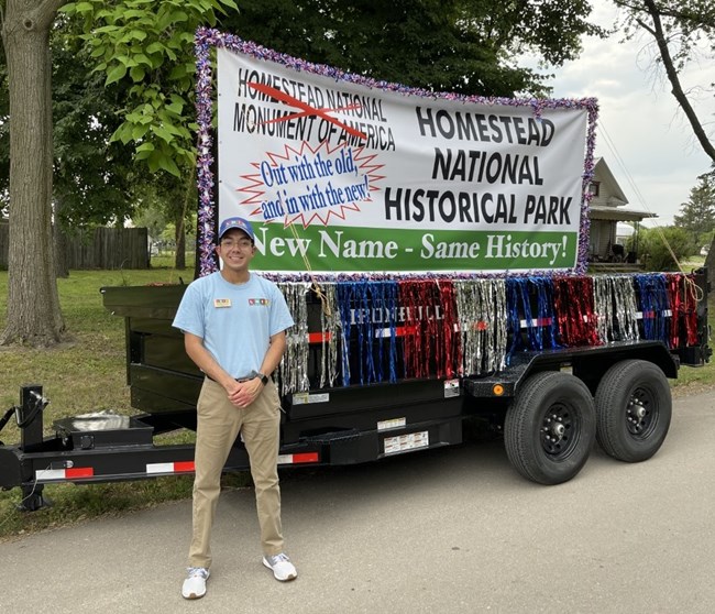 Kristian posing in front of caravan truck with poster that reads: homestead national historical park - out with the old and in with the new