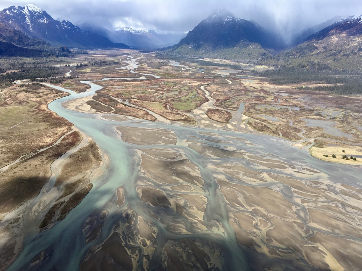 Aerial view of a mountain landscape and braided channels of water and sand bars