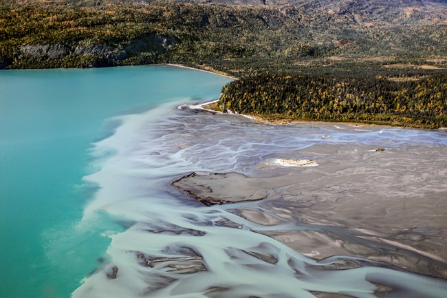 Image of freshwater flowing into a clear blue lake.