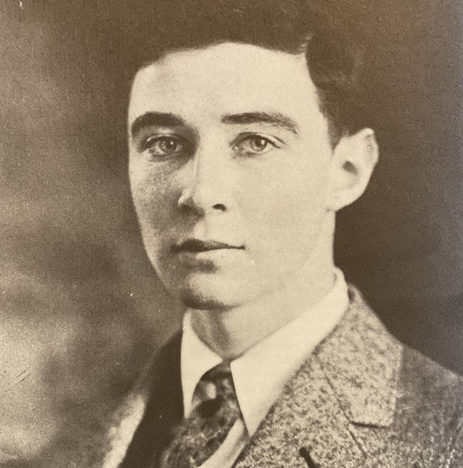 A sepia photo of a young man in a suit.