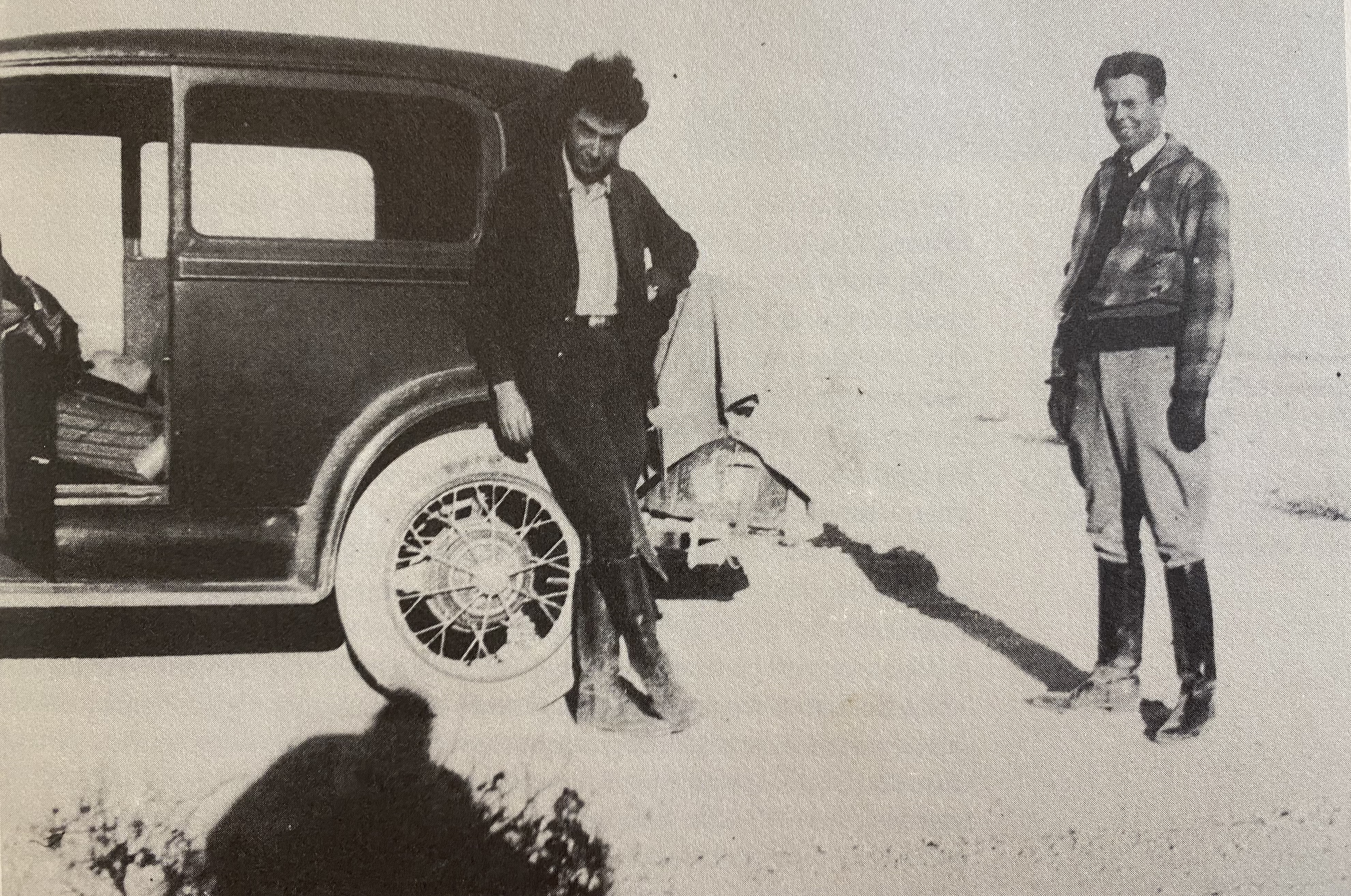 Oppenheimer and Ernest Lawrence. Black and white photo of Oppenheimer and Ernest Lawrence standing next to a car in the New Mexico desert.