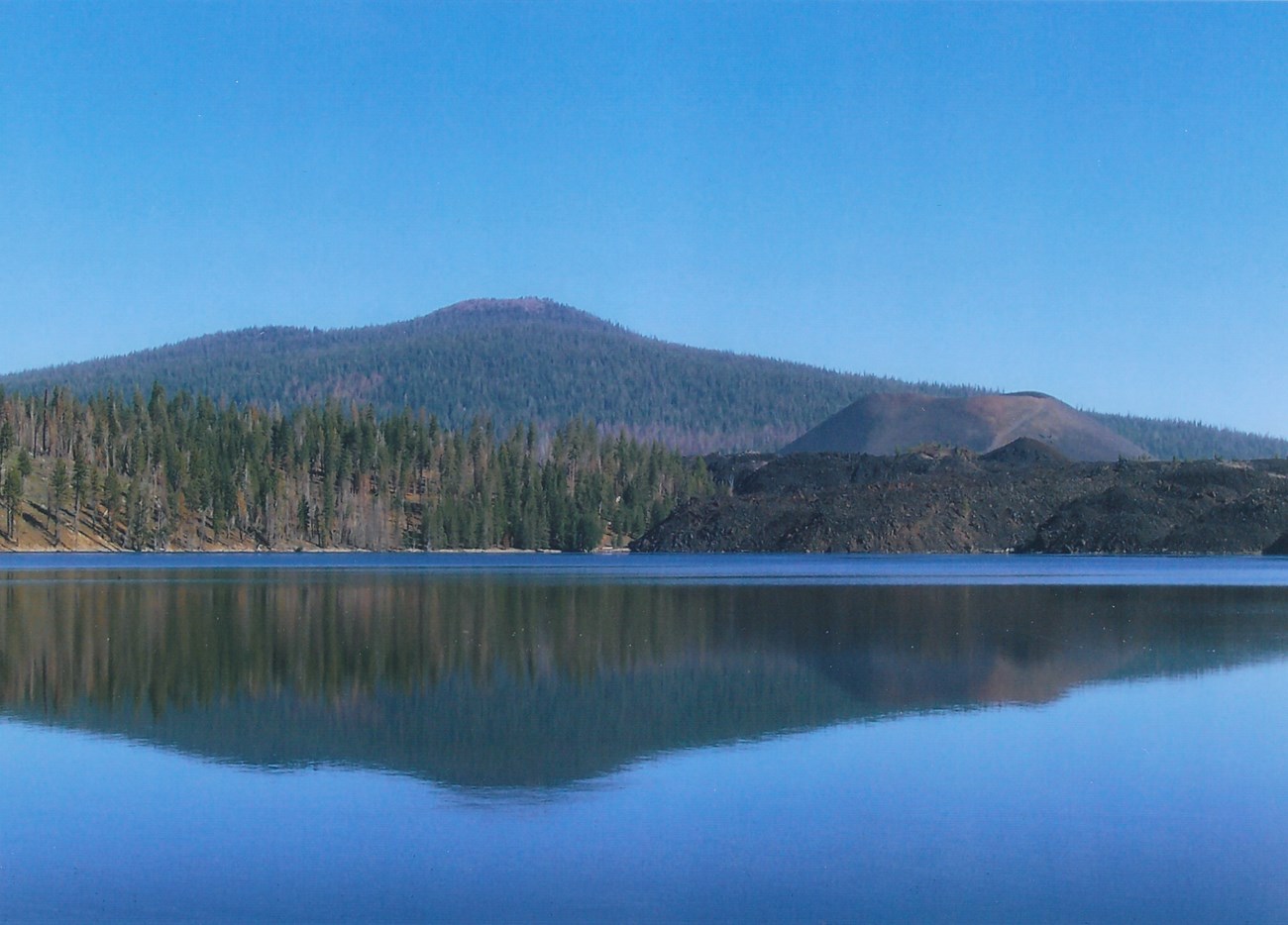 photo of volcanic peaks in the distance and a lake in the foreground.