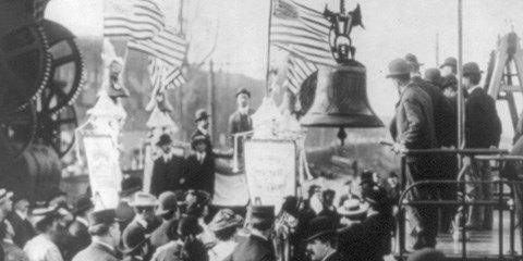 A crowd watching the Liberty Bell get hoisted onto a train car.