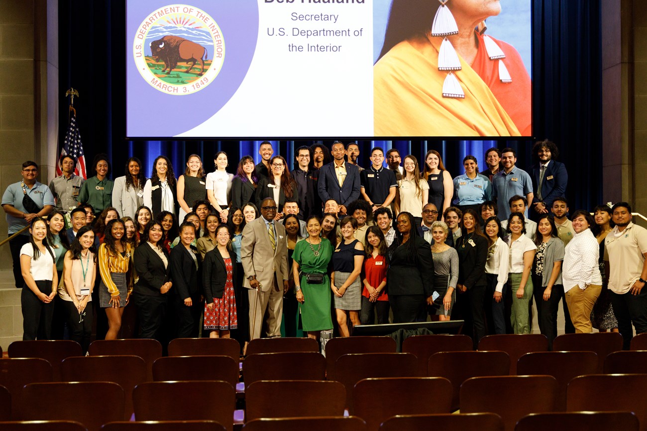 Group of interns, NPS staff, and partners with Secretary Deb Haaland at the U.S. Department of the Interior