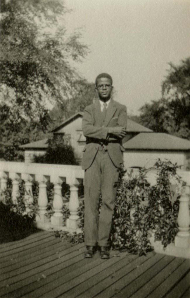 LONG 1002-9-4-1141 Candid portrait of a Black man standing outside on a porch.