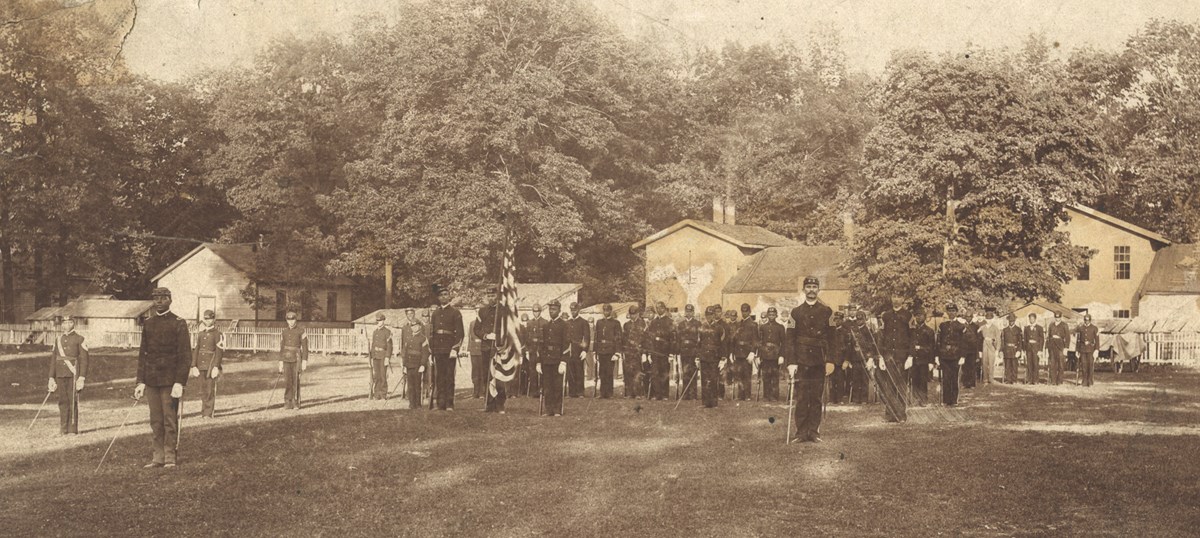 Black and white photo of soldiers standing at attention in a military barracks