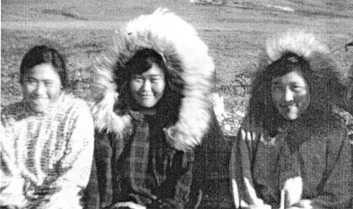Rhoda Tatqavina Morry(-Aghook), left, and Molly Kunnaana Mekiana, right, both made the "Long Walk" from Killiq to Tulugaq where they met up with their friend Ethel Qaunnaq Ahgook, center Black-and-white photograph of three young Alaska Native women sitting together