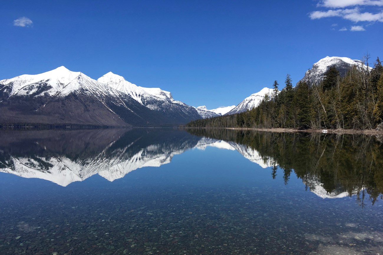 snow capped mountains reflect on a calm lake