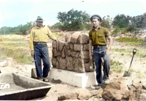 two young men stand in front of a pile of carefully-placed large stones
