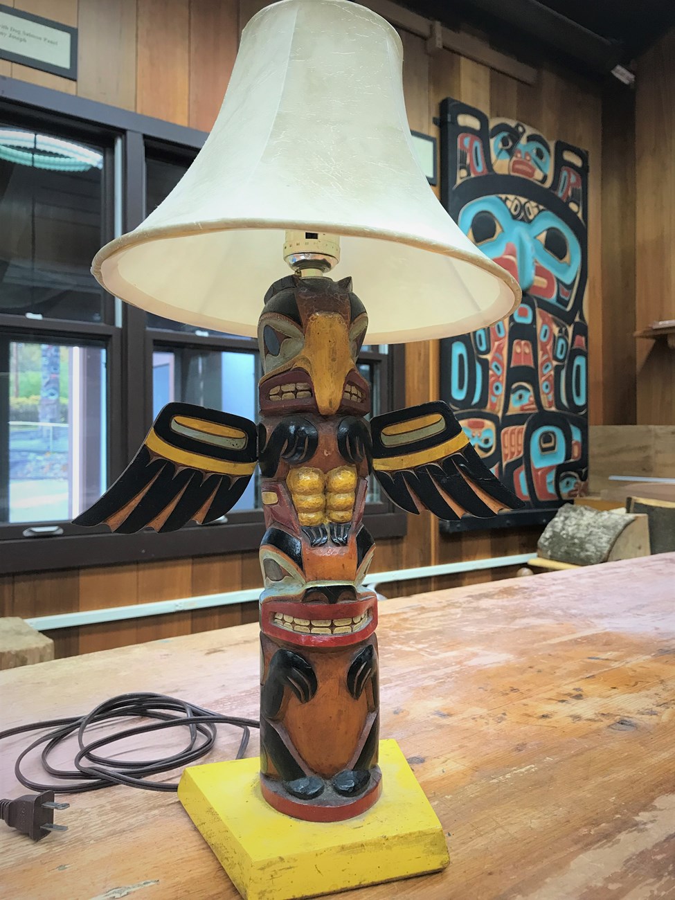 A Table lamp carved to resemble a totem pole with an eagle and a bear represented.