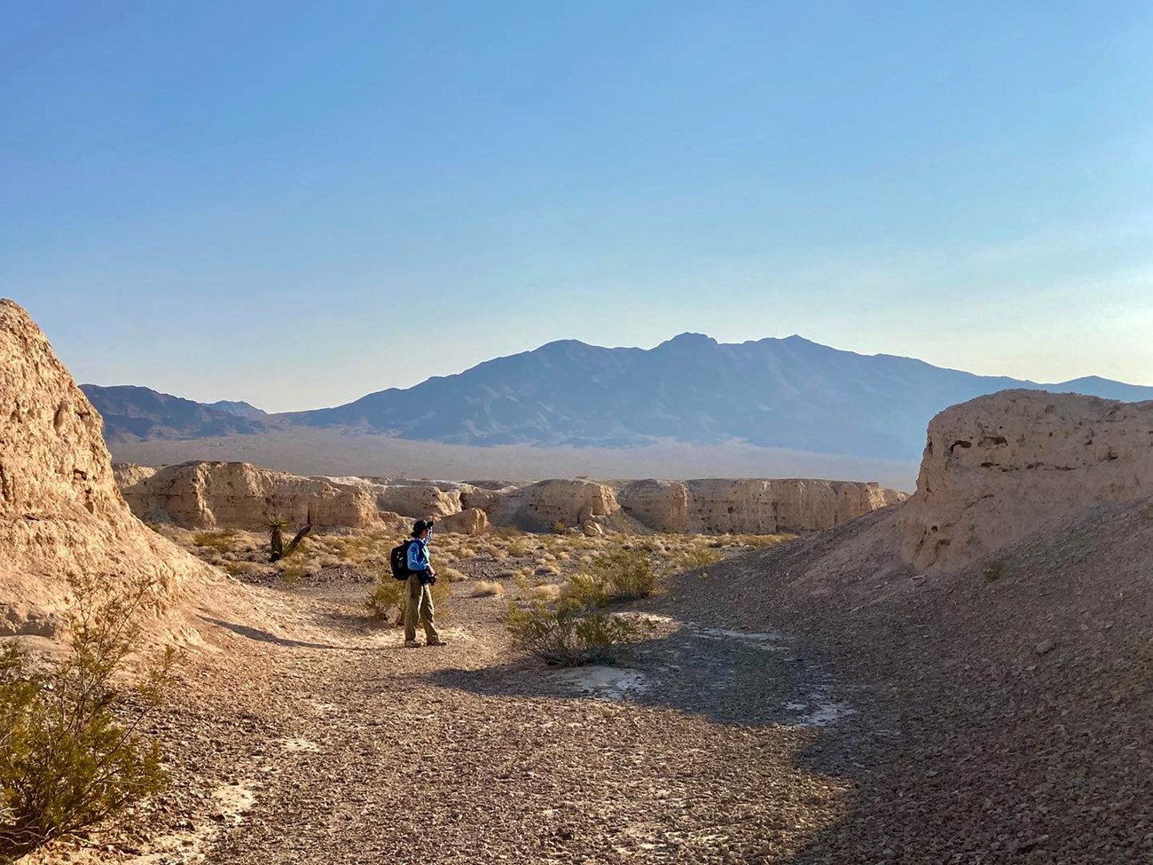 a person stands in the middle of a desert wash with rock formations all around