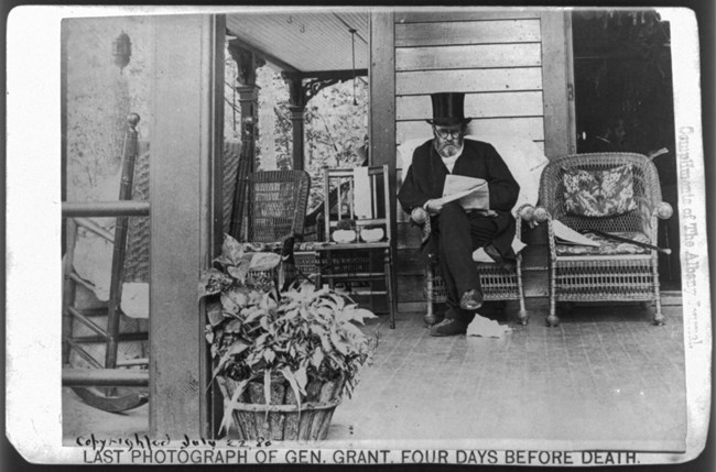 Black and white photo of a man on a rocking chair with a hat and glasses,