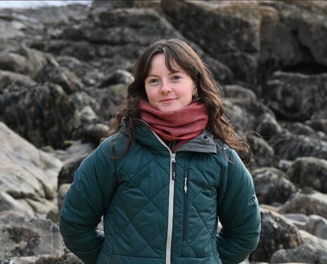 Portrait of Lauren Knierim, a young woman smiling outdoors in front of rocks.