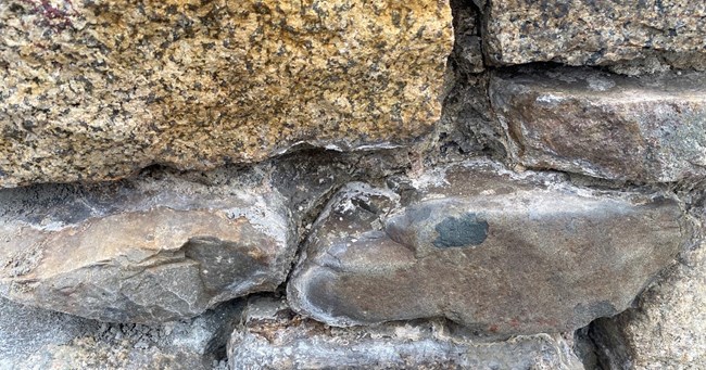Blast Furnace chimney A close-up of multi-colored stones with the mortar chipped out from between the joints.