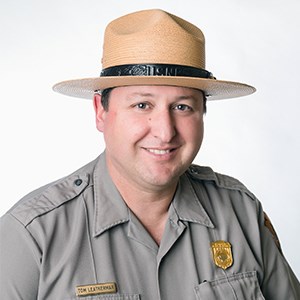 Portrait of smiling man in flathat and National Park Service Uniform.