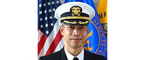 Formal portrait of Leo smiling in uniform in front of the American flag.