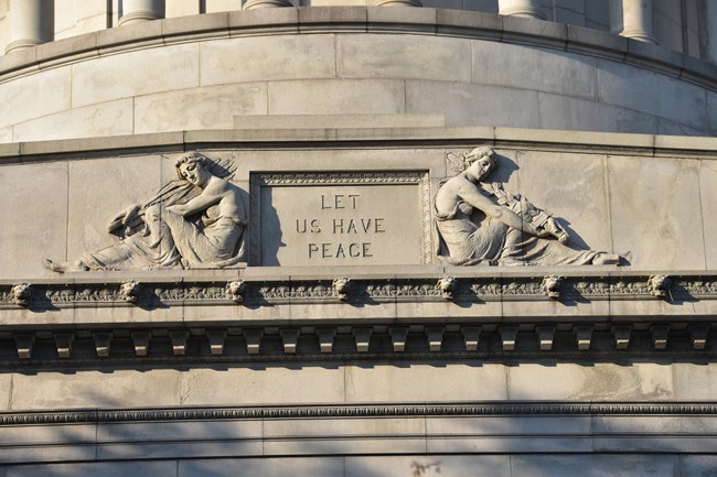 White granite epitaph with Let Us Have Peace text and two allegorical figures on the left and right