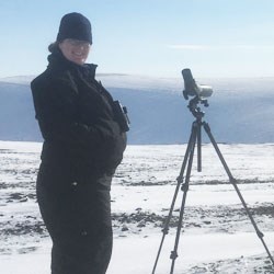 Picture of Letty Hughes standing in a snowy field in front of an instrument mounted on a tripod.